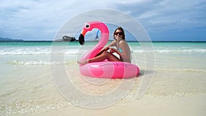 girl floats on an inflatable mattress on the beautiful white beach with clear water