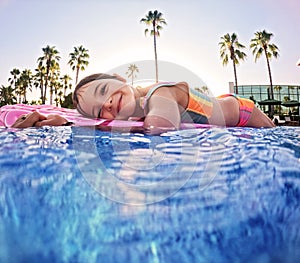 Girl floats on pink inflatable in the pool. Beach resort vacation by the sea. Winter and summer seaside resort holidays