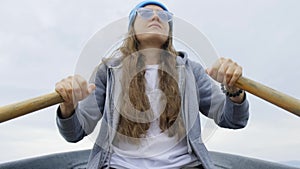 A girl floats on a rowing boat. Woman rowing while sitting in a boat.