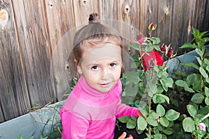 Girl in a flower bed with red roses