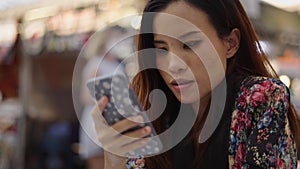 A girl in a flower dress looks at her mobile phone