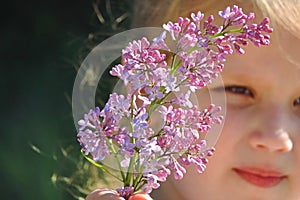 Girl with a flowering sprig of lilac, selective focus