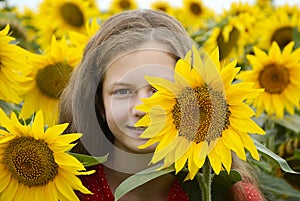Girl with flowing hair looks into the lens with a flower of a sunflower on half of the face