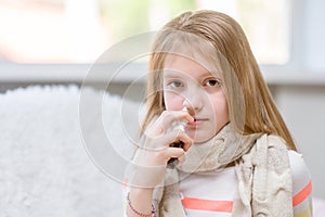 Girl with flu using nose spray