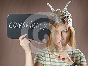 Girl in a foil hat with a sign saying conspiracy