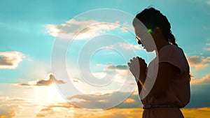 Girl folded her hands in prayer silhouette at sunset. slow motion video. Girl folded her hands in prayer pray to God