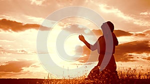Girl folded her hands in prayer silhouette at sunset. woman praying on her knees. slow motion video. concept