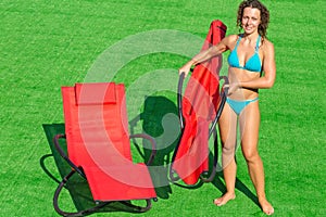 Girl folding deck-chair on green field