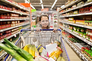 Girl with food in shopping cart at grocery store