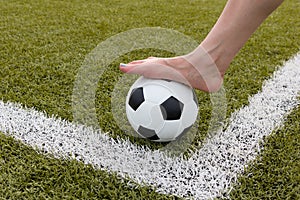 Girl foot on the soccer ball on green field