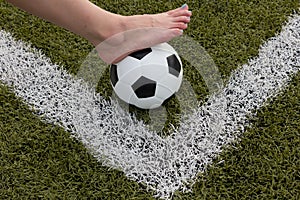 Girl foot on the soccer ball on green field