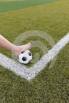 Girl foot on the soccer ball on green field
