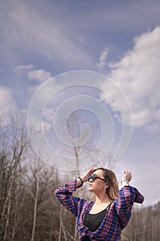 Girl on the forest stands and looks up at the sky