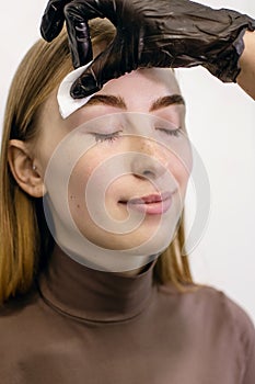 A girl with freckles in a beauty salon uses the services of a beautician