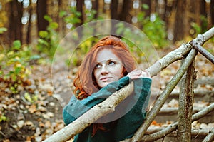 Girl with freckles and blue eyes dreaming in autumn forest