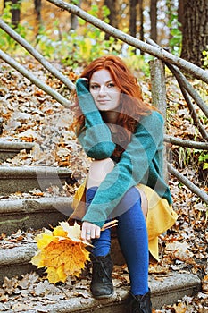 Girl with freckles and blue eyes dreaming in autumn forest