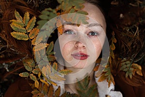 Girl with freckles lies in the grass and looks into the camera