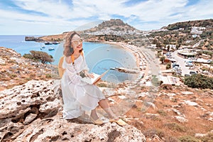 Girl freelancer or student working with laptop computer outdoors overlooking the sea Bay and the ancient city on the