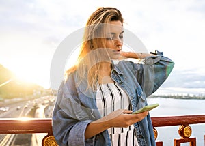 Girl freelancer at sunset speaks on the phone and works