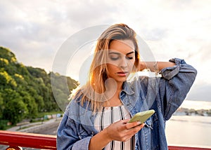 Girl freelancer at sunset speaks on the phone and works
