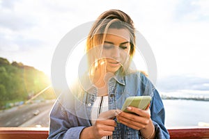 Girl freelancer at sunset speaks on the phone and works