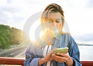 Girl freelancer at sunset speaks on the phone and works