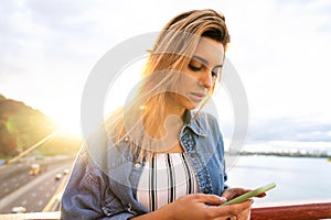 Girl freelancer at sunset speaks on the phone and works