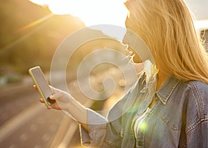 Girl freelancer at sunset speaks on the phone and works