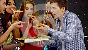 Girl with friends dancing and eating slice of pizza in nightclub. 4k.