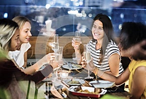 Girl friends having a dinner together at a rooftop bar