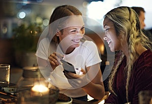 Girl friends having a dinner together at a rooftop bar using a s