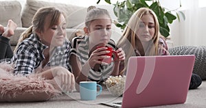 Girl friends having snack while watching media content on laptop