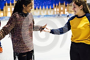 Girl friends ice skating on the ice rink together