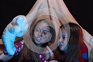 Girl friends playing with toys in blanket tent