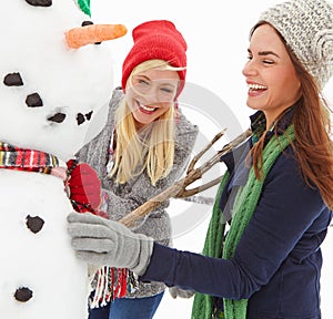 Girl friends, snowman and winter fun activity of women on a Christmas holiday, travel and vacation. Happiness, laughing