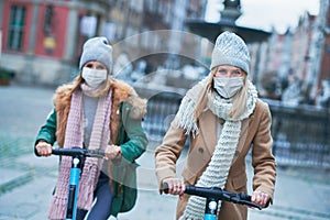 Girl friends wearing face masks and commuting on scooter in the city