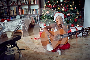 Girl in front of decoration Christmas tree play guitar