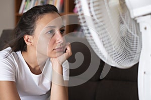 Girl in front of electric fan trying to refresh herself