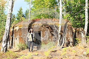 Girl in front of military bunker hidden in forest