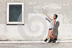 Girl in front of and old wall pointing a window with one arm