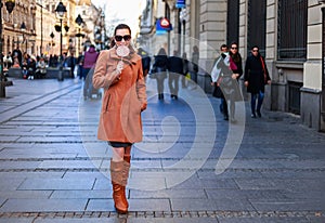 Girl in full lenght standing and holding a lollipop in the city