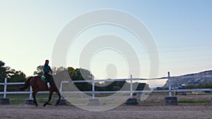 A girl galloping on horseback at outdoor manege