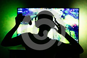 Girl gamer in headphones in the dark on tv background. Ability to use as background. Silhouette