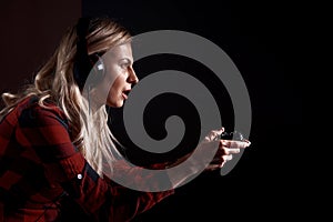 Girl gamer in headphones and with a joystick enthusiastically playing on the console