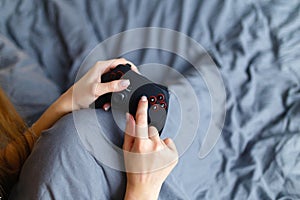 Girl gamer playing video game with wireless joystick at home. Gamepad in female hands close-up, gaming addiction concept, woman