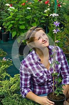 Girl gardener looks at tall flower in a greenhouse