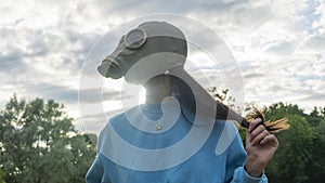 Girl in a gas mask in the rays of the sun. Alienation in the city. Fashion, ecology and loneliness concepts