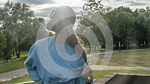 Girl in a gas mask in the rays of the sun. Alienation in the city. Fashion, ecology and loneliness concepts