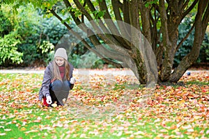 Girl gathering autumn leaves in park