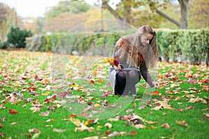 Girl gathering bright autumn leaves